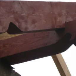 Drewniana konstrukcja dachu z ozdobnymi wykończeniami, pomalowana na brązowo, widoczna z dołu.